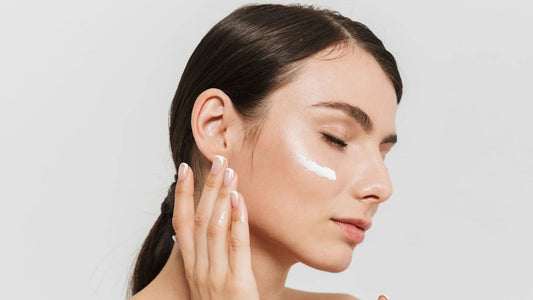 Dropper with a pale pink serum over shimmering water